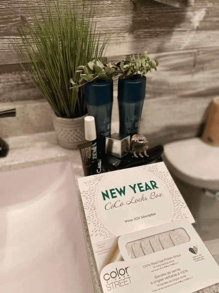 Bathroom countertop with Color Street nail polish strips box, two blue glasses, and a potted plant.