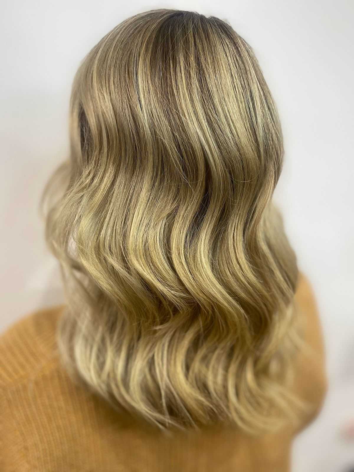 Blonde wavy hair styled in loose curls, viewed from the back, with a soft, natural look.
