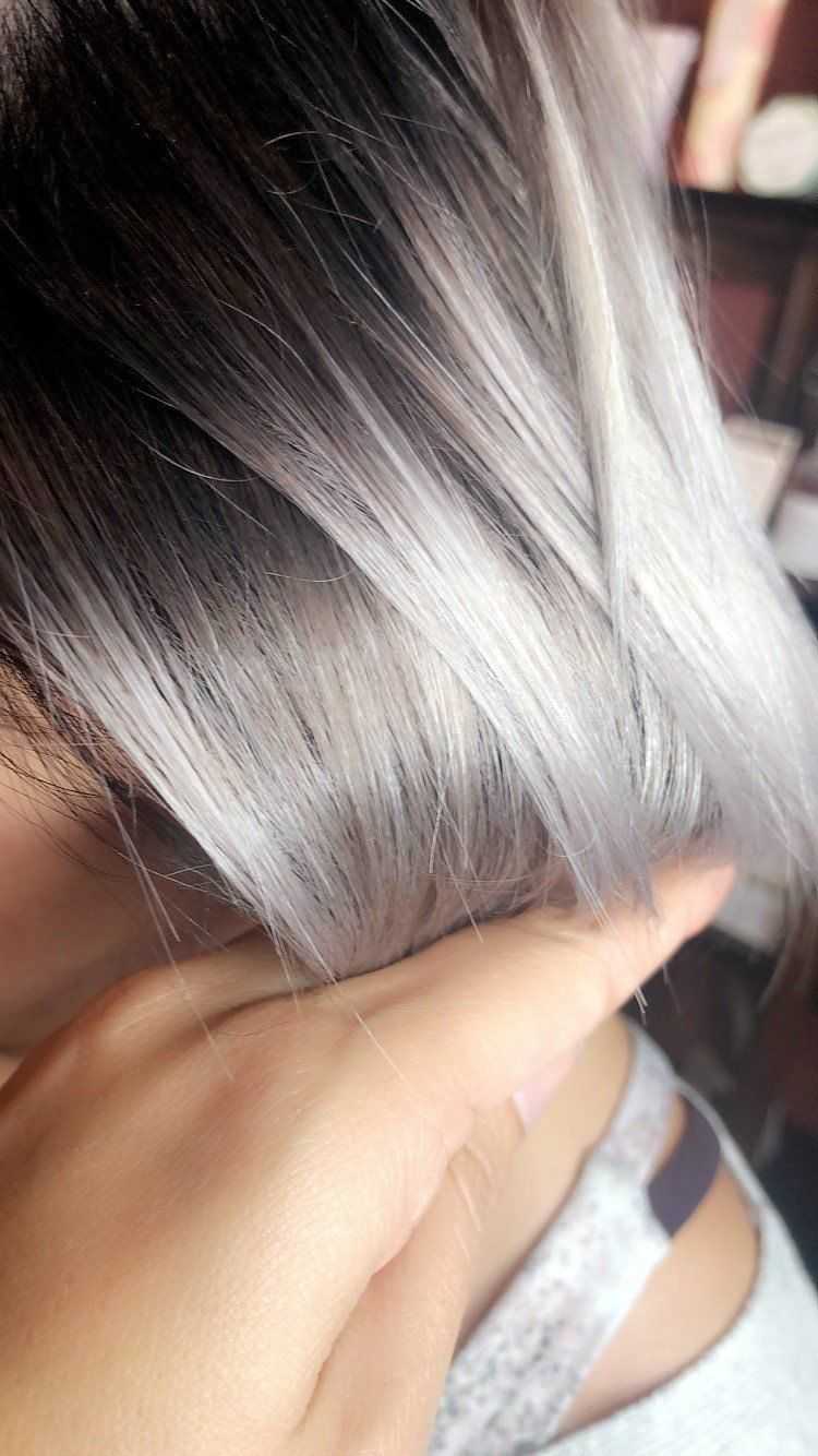 Hand holding hair with silver and black streaks, showcasing a fresh dye job.